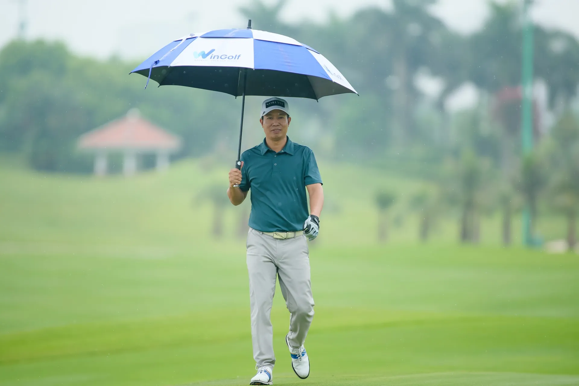Golfer cầm ô WinGolf thi đấu dưới mưa tại sân Long Biên